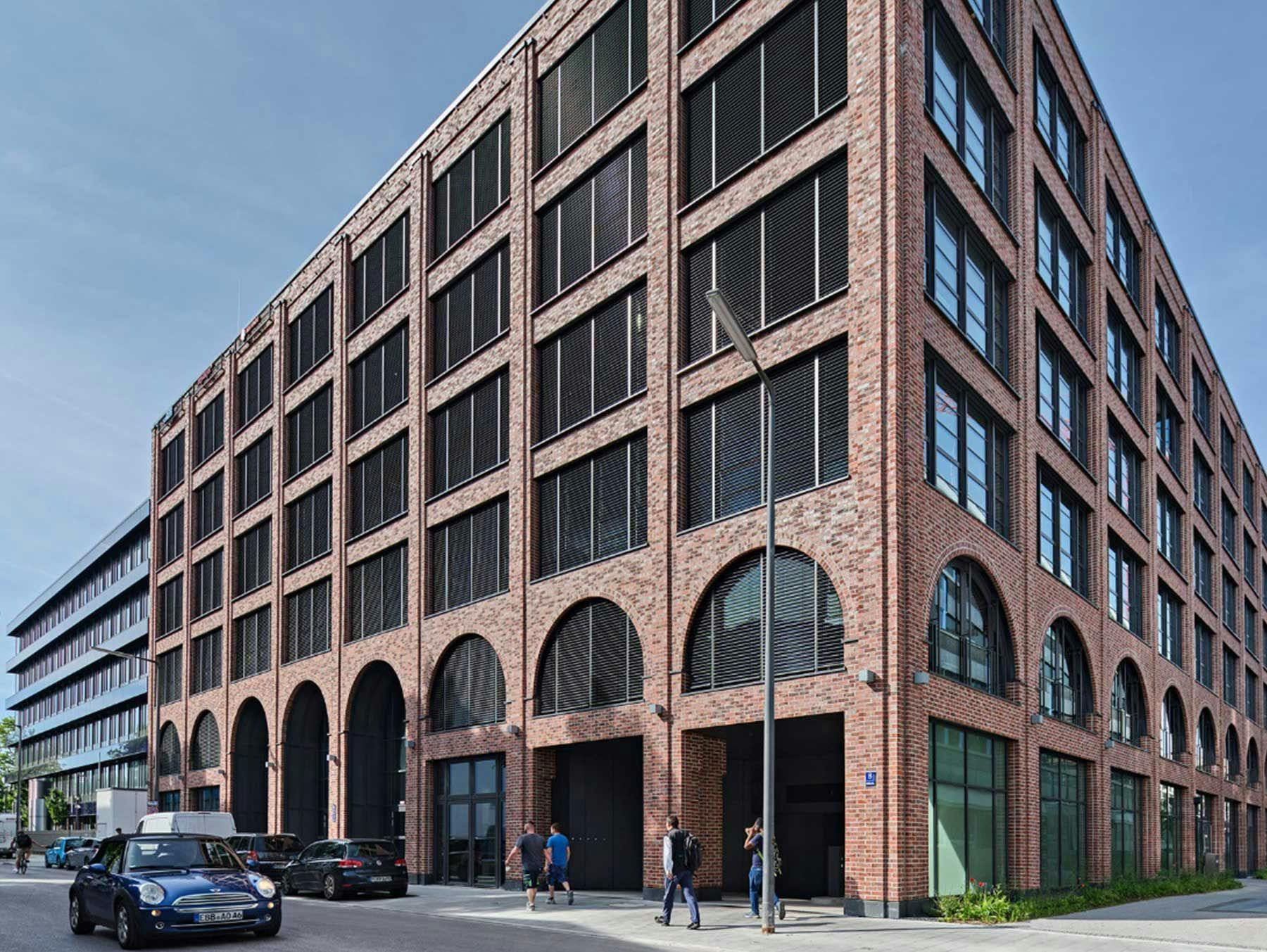 Rendering eines modernen Bürogebäudes mit Backsteinfassade und großen halbrunden Fenstern. 